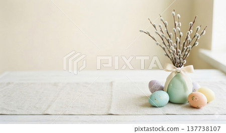 A serene Easter decoration featuring pastel-colored eggs arranged next to a mint green vase filled with pussy willow branches 137738107