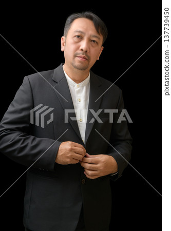Confident Businessman in Black Suit Adjusting Jacket on Black Background Confident Businessman in Black Suit Adjusting Jacket on Black Background 137739450