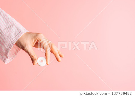 Hand holding a dental floss container on pink background, clean oral care product with copy space Hand holding a dental floss container on pink background, clean oral care product with copy space 137739492