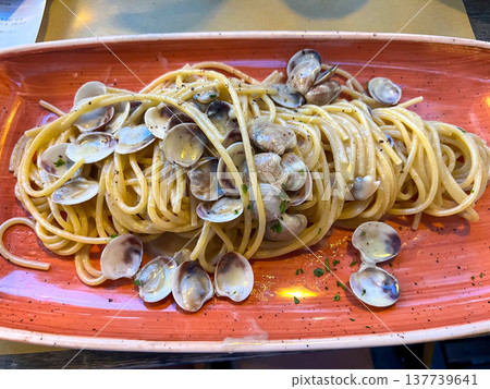 View of a full plate of Italian pasta vongole on a trattoria table in Italy View of a full plate of Italian pasta vongole on a trattoria table in Italy 137739641