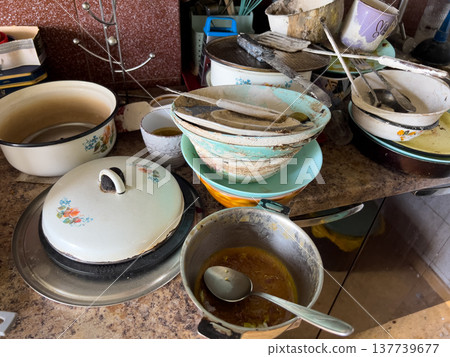 Large pile of various dirty dishes on a kitchen table. Abandoned, dirty kitchen Large pile of various dirty dishes on a kitchen table. Abandoned, dirty kitchen 137739677