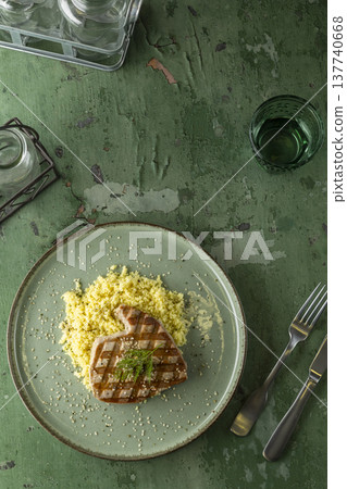Grilled tuna steak with couscous on rustic table Grilled tuna steak with couscous on rustic table 137740668