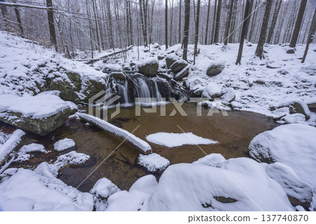Waterfall cascading through snowy forest in Liberecky kraj Waterfall cascading through snowy forest in Liberecky kraj 137740870