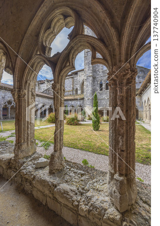 Ornate stone arches framing cloister garden in La Romieu Ornate stone arches framing cloister garden in La Romieu 137740904