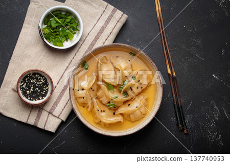 Gyoza dumplings broth soup chopsticks dark background bowl asian wontons Gyoza dumplings broth soup chopsticks dark background bowl asian wontons 137740953