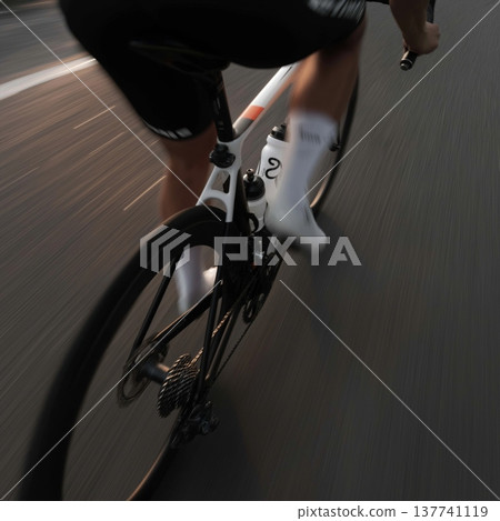 Cyclist propelling modern road bike forward on asphalt road. Cyclist riding bicycle with motion blur, emphasizing speed, fitness, and movement 137741119