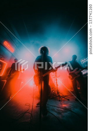 Live band performing during an energetic music concert. Musicians playing rock music on stage with dramatic red and blue lighting 137741160