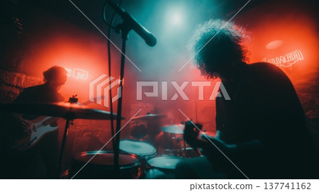 Live band performing during an energetic music concert. Musicians playing rock music on stage with dramatic red and blue lighting Live band performing during an energetic music concert. Musicians playing rock music on stage with dramatic red and blue lighting 137741162