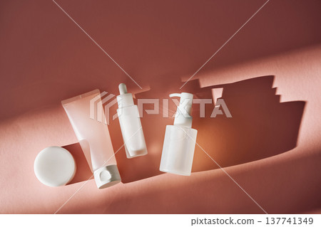 Skincare product bottles with dropper and pump on pink background Skincare product bottles with dropper and pump on pink background 137741349