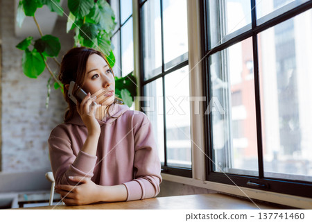一位女士在窗邊用手機通話。 137741460