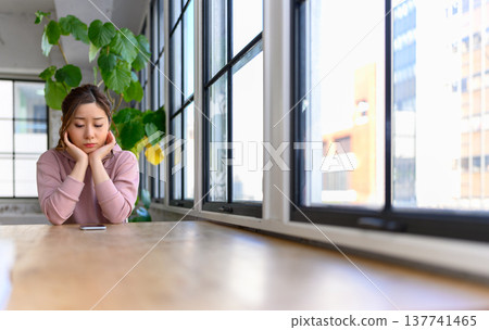 A young woman thinking at the window side A young woman thinking at the window side 137741465