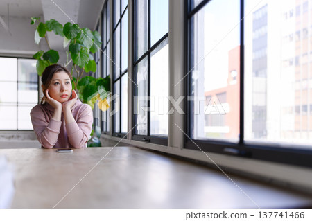Pensive woman by the window Pensive woman by the window 137741466