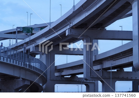 黃昏時的橫濱港北樞紐:錯綜複雜的架空橋樑和巨大的橋墩交錯縱橫。 黃昏時的橫濱港北樞紐:錯綜複雜的架空橋樑和巨大的橋墩交錯縱橫。 137741560
