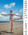 Woman yoga practice at the beach in Utthita Hasta Padangusthasana Extended Hand-to-Big-Toe Pose 137741689