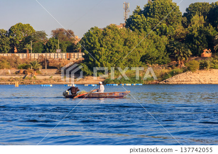 Two egyptian men fishing with fishing nets in old rowing boat on Nile river Two egyptian men fishing with fishing nets in old rowing boat on Nile river 137742055
