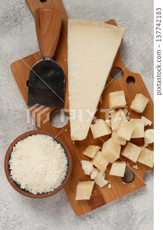 Freshly sliced and grated cheese, parmesan cheese, on a wooden chopping board, rustic style, no people 137742183