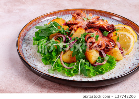 Grilled octopus with baked potatoes and fresh herbs, on a decorative plate, homemade, 137742206