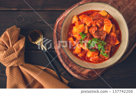 Stew with potatoes, in tomato sauce, with spices and herbs, close-up, no people, on a black background Stew with potatoes, in tomato sauce, with spices and herbs, close-up, no people, on a black background 137742208