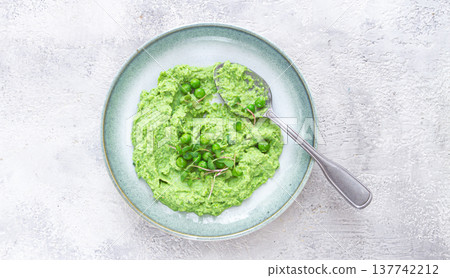 Delicious green pea puree served in a stylish bowl garnished with fresh peas and microgreens for a healthy meal Delicious green pea puree served in a stylish bowl garnished with fresh peas and microgreens for a healthy meal 137742212