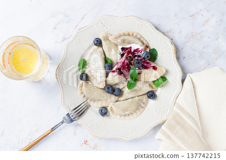 Delicious homemade dumplings served with berry sauce and fresh blueberries on a white plate 137742215