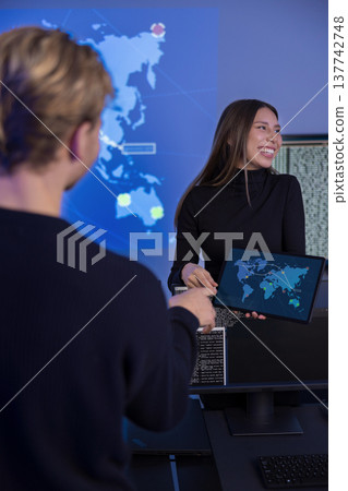 Security professionals collaborating in a technical workspace with threat maps displayed Security professionals collaborating in a technical workspace with threat maps displayed 137742748