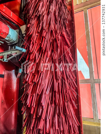 Automatic car wash machine with large red rotating brushes for cleaning vehicles. 137742931
