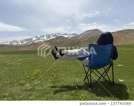 Relaxing mountain scenery. Mountains person chair.mountains in spring silhouette of a tourist Relaxing mountain scenery. Mountains person chair.mountains in spring silhouette of a tourist 137743569