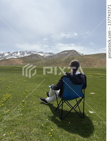 Relaxing mountain scenery. Mountains person chair.mountains in spring silhouette of a tourist Relaxing mountain scenery. Mountains person chair.mountains in spring silhouette of a tourist 137743571