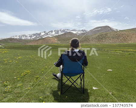 Relaxing mountain scenery. Mountains person chair.mountains in spring silhouette of a tourist Relaxing mountain scenery. Mountains person chair.mountains in spring silhouette of a tourist 137743574