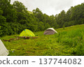 Two colorful camping tents on a forest glade during rain. 137744082