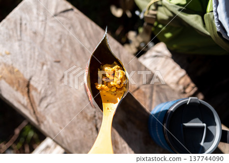 Hiker s freeze-dried meal on a plastic spoon over a food pouch. Hiker s freeze-dried meal on a plastic spoon over a food pouch. 137744090