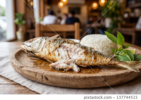 Fried Thai mackerel fish with rice and basil on wooden plate 137744515