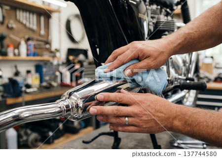 Mans hands polishing chrome exhaust pipe on motorbike 137744580