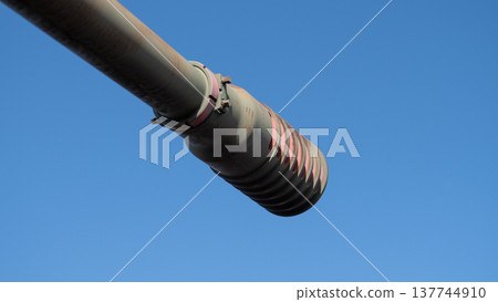 Barrel Cooling Fins Detail Against Clear Sky, Concentric Rings And Clamps Visible With Paint Scuffs, Industrial Cooling Solution And Rugged Hardware Conveys Fieldready Durability And Heat 137744910