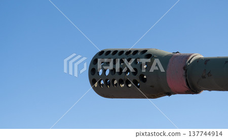 Industrial Suppressor Against Sky Showing Vent Pattern And Holes. Extreme Closeup Of Muzzle Suppressor Emphasizing Circular Vent Design And Industrial Aesthetic Against Clear Blue Sky Industrial Suppressor Against Sky Showing Vent Pattern And Holes. Extreme Closeup Of Muzzle Suppressor Emphasizing Circular Vent Design And Industrial Aesthetic Against Clear Blue Sky 137744914