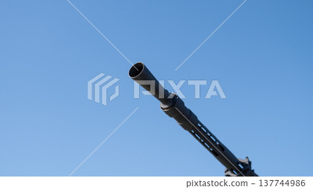 Gun Barrel Pointing Into Blue Sky, Closeup Of Helicopter Mounted Cannon Emphasizing Metal Detail, Textured Surface, Rivets, Sun Glare, Tactical Readiness, Defense Posture, Aviation Security, Gun Barrel Pointing Into Blue Sky, Closeup Of Helicopter Mounted Cannon Emphasizing Metal Detail, Textured Surface, Rivets, Sun Glare, Tactical Readiness, Defense Posture, Aviation Security, 137744986