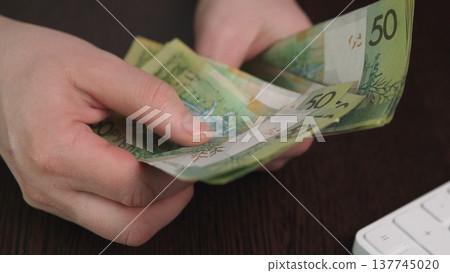 Professional Handling Of Currency Notes. Counting And Stacking Banknotes At Office Desk. Expert Handling Of Paper Currency With Precise Gestures And Organized Stacks At Workplace 137745020