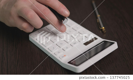 Calculator Hand Pressing Numeric Keys, Business Analyst Calculating Expenses On Dark Wood Desk With Pen And Glasses, Focused Professional Mood, Closeup Emphasizing Precision And Workflow Calculator Hand Pressing Numeric Keys, Business Analyst Calculating Expenses On Dark Wood Desk With Pen And Glasses, Focused Professional Mood, Closeup Emphasizing Precision And Workflow 137745025