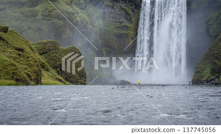 Wide shot of huge waterfall and river with people walking around, Iceland Wide shot of huge waterfall and river with people walking around, Iceland 137745056