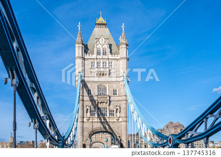 Tower Bridge stands majestically against a clear blue sky in London. The architectural design showcases stone and steel elements, highlighting its historical significance and beauty. 137745316
