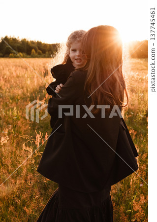Mother Embraces Daughter. Gentle Silhouette Of Mother Shielding Daughter In Field Glow 137745461