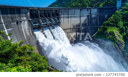 日本一座巨型水壩噴湧而出的壯觀水景。背景素材為藍天水面紋理，並留有充足的文字空間。 137745780