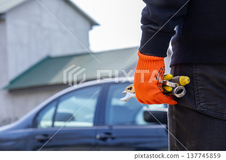 A mechanic stands confidently, gripping keys and tools, preparing to repair a vehicle in a bustling garage, where trade meets artistry 137745859