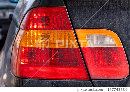 Radiant glow from the taillight of a stylish car brings life to the evening as it navigates through a vibrant urban landscape Radiant glow from the taillight of a stylish car brings life to the evening as it navigates through a vibrant urban landscape 137745884