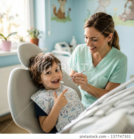 A cheerful little boy sitting in a dentist chair smiles brightly while a friendly female pediatric dentist performs a routine oral exam.. High quality photo 137747301