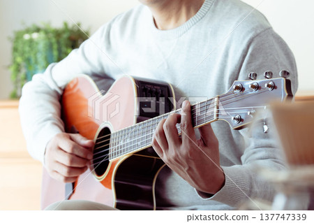 一位中年男子彈吉他的手 137747339