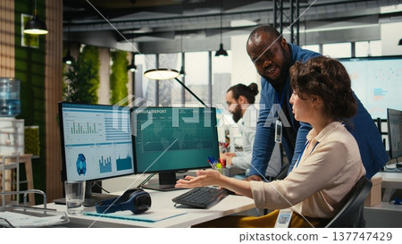 Diverse office coworkers reviewing monthly data graphs to create reports, applying business strategy and analysis to drive innovation and improve company performance. Work alliance. 137747429
