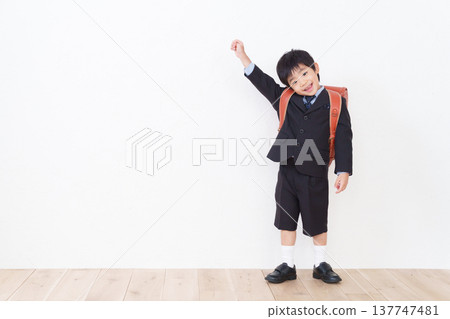 一名小學一年級男生背著書包(參加入學典禮,穿著正式西裝)。 一名小學一年級男生背著書包(參加入學典禮,穿著正式西裝)。 137747481