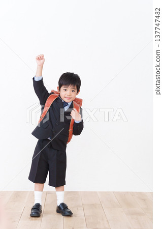 一名小學一年級男生背著書包(參加入學典禮,穿著正式西裝)。 一名小學一年級男生背著書包(參加入學典禮,穿著正式西裝)。 137747482