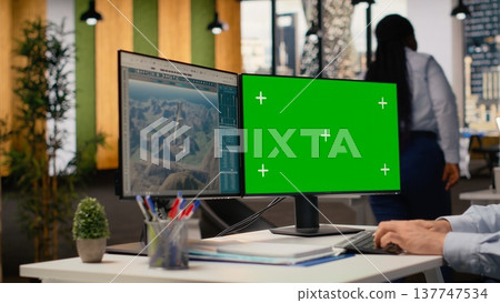 Engineer working on futuristic wind turbine concept on green screen PC designed for clean energy output. Man in office uses mockup computer to research cutting edge VAWT innovation, camera B Engineer working on futuristic wind turbine concept on green screen PC designed for clean energy output. Man in office uses mockup computer to research cutting edge VAWT innovation, camera B 137747534